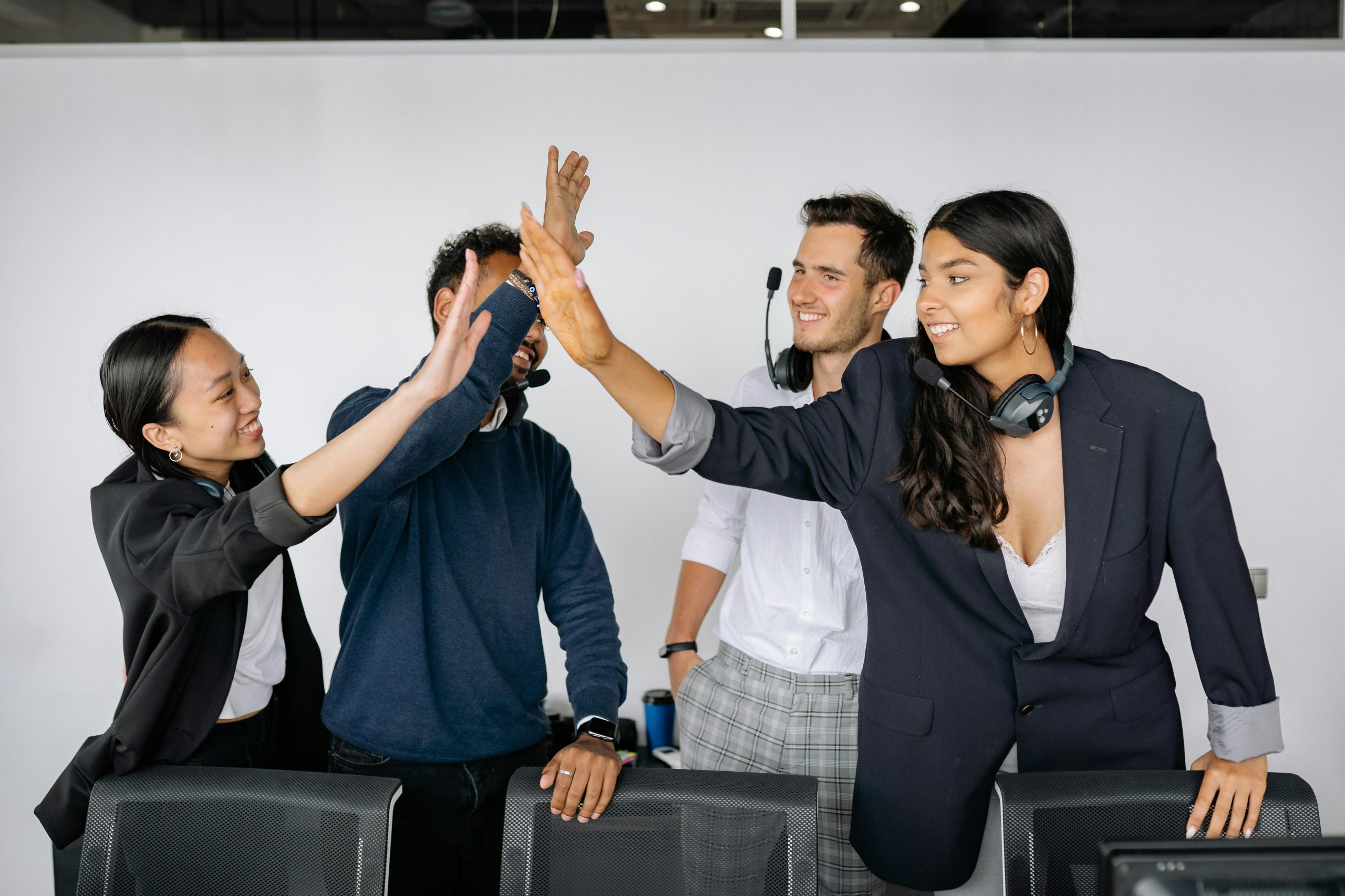 A group of diverse office employees celebrating teamwork with a high five.